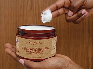 Zoomed-in image of SheaMoisture hair masque being scooped in hand against woody background.