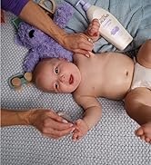 Baby on a bed next to a bottle of Baby Jergens Lotion