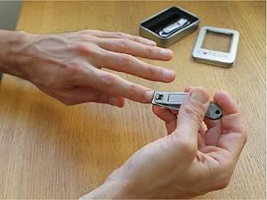 A person clips their left index finger with a pair of Cuticor nail clippers.