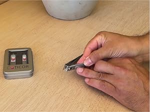 A person files a finger on their right hand with a Cuticor nail clipper.