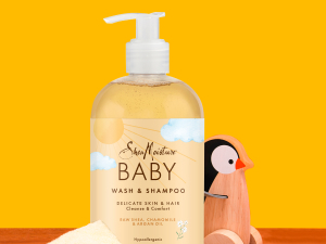Pump bottle  with shea butter pieces and penguin child toy against yellow background.