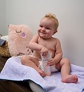 Baby sitting on changing table holding ointment