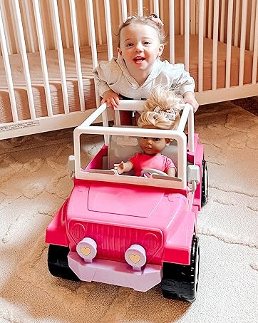 a child pushes her doll sized jeep with doll