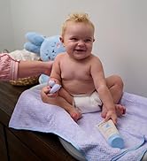 Baby on a changing table holding a bottle of skin cream