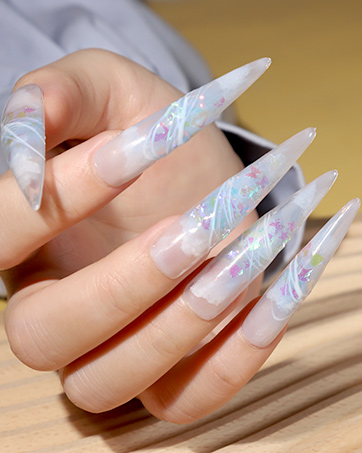 Long, pointed acrylic nails with iridescent, holographic design. Stiletto shape with swirling pastel patterns.