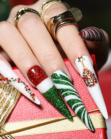 Hand displaying festive Christmas-themed acrylic nails with glitter, snowflakes, and candy cane designs. Gold rings visible on fingers.