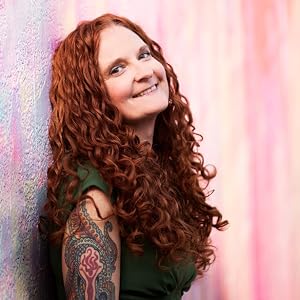 smiling red curly haired woman leaning against pink wall