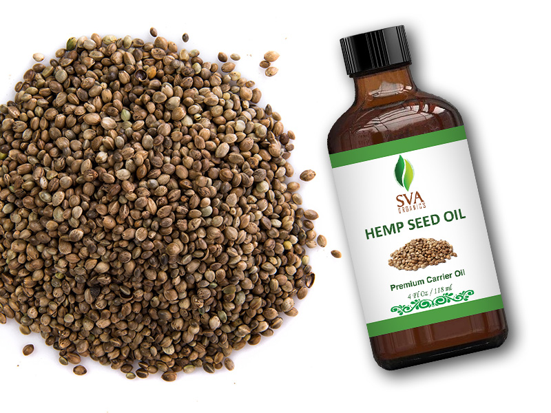 An amber glass 4oz bottle of hemp seed carrier oil placed alongside of raw hemp seeds