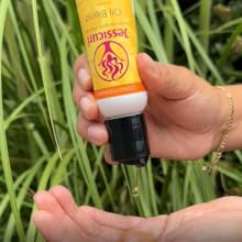 hand holding oil blend product and dripping it out onto another hand 
