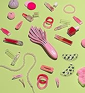 pink curl detangler on green background surrounded by makeup and hair accessories